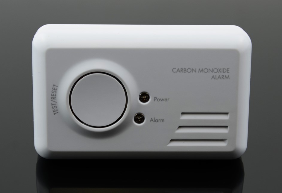 Carbon monoxide detector on a gray wall.